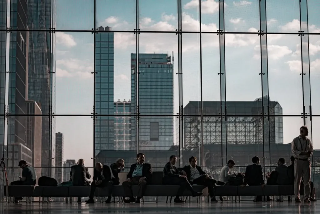 Corporate Shuttle Service: What the Setup Actually Involves 4 Business professionals waiting in a conference center lobby with a city skyline view